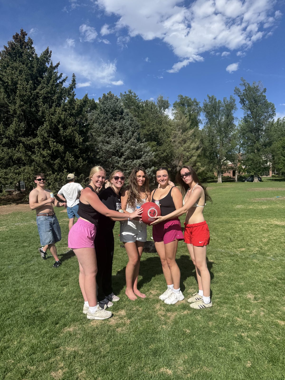 Olivia and friends posing together with a kickball on a sunny park field